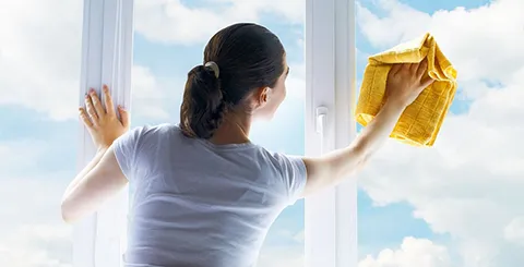 Person cleaning a large window with a cloth